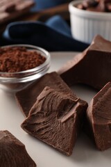 Pieces of tasty milk chocolate and powder on plate, closeup