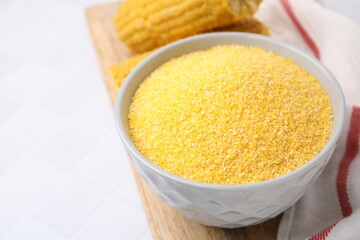 Raw cornmeal in bowl on white table, closeup. Space for text