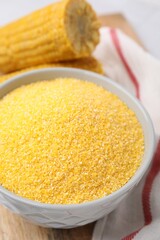 Raw cornmeal in bowl on table, closeup