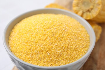Raw cornmeal in bowl on white table, closeup