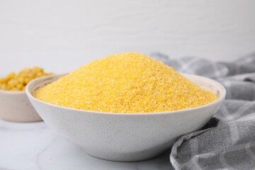 Raw cornmeal in bowl on white table, closeup