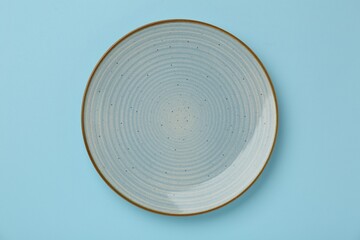 Beautiful ceramic plate on light blue background, top view