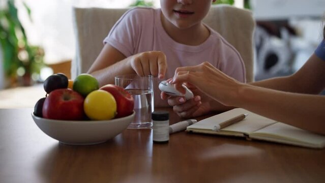 Nurse checking girl's blood glucose level using a fingerstick glucose meter.