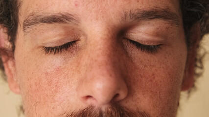Obraz premium Detailed close-up shot of man with closed eyes studio on beige background