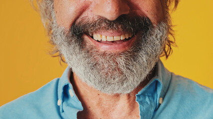 Close up of lips of a smiling with white teeth older man, isolated on an orange background