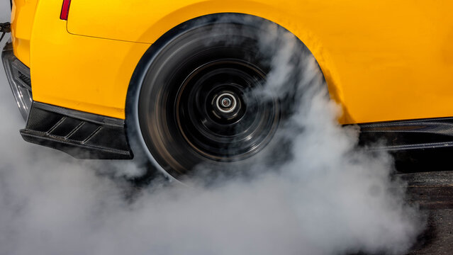 Car burnout wheels tire with white smoke,Car wheel burnout with smoke from the spinning tyre, Drag car wheel burns tires preparation for the race. © Darunrat
