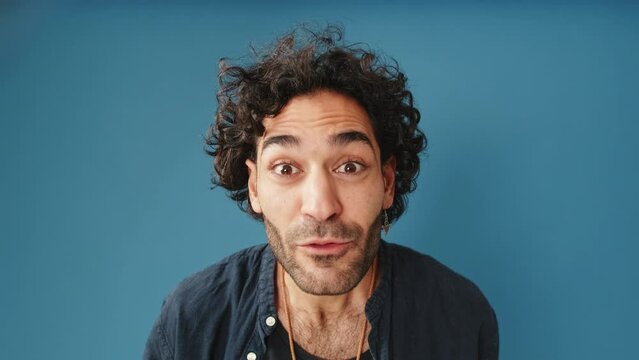 Man looking at camera looking for something isolated on blue background in studio