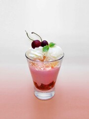 This is an image of a strawberry pink drink. Berry smoothie. milkshake. Ice cream and cherry are on top. The background is also a pink gradation. Cool and refreshing. Taken from slightly above