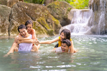 Group of Young Asian man and woman enjoy and fun outdoor lifestyle travel nature forest mountain on summer holiday vacation. Happy generation z people friends playing water together at waterfall.