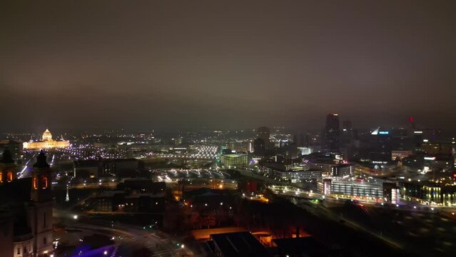 High drone footage of Minnesota cityscape with illuminated buildings at night under cloudy sky, USA