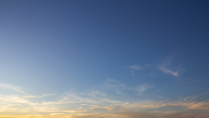 Clouds are wispy and white, with a hint of orange from the setting sun.