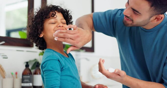 Father, child and shaving cream on face, learning to play or happy together in home bathroom. Kid, boy and dad apply foam, skincare or bonding in morning routine, facial cosmetics or cleaning hygiene