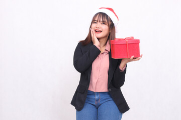 Beautiful asian girl in suit smiling with Santa Claus hat posing with Christmas gift box and lifting box and holding chin on white background for promotion, advertising, banner, billboard