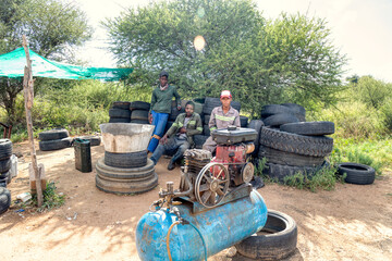 Fototapeta na wymiar african man entrepreneur fixing tires on the side of the road