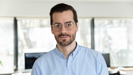 Profile picture of young Caucasian man in glasses pose in office. Headshot portrait of confident 20s businessman in spectacles feel confident successful at workplace. Employment concept.