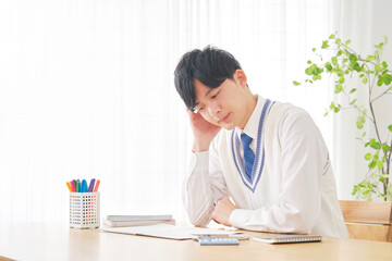 自宅で勉強中に考える男子高校生