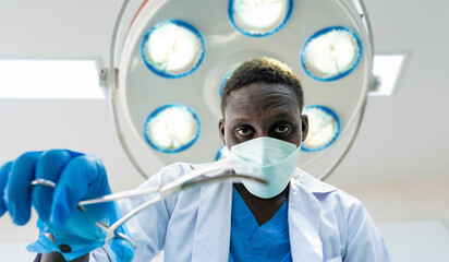 African surgeon doctor is performing operation using curved hemostat for heart or brain surgery in...