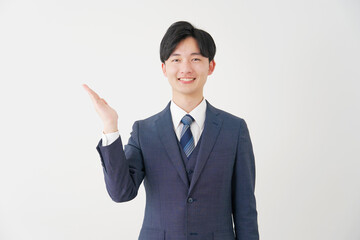 手のひらで左側を指すビジネスマン　白背景