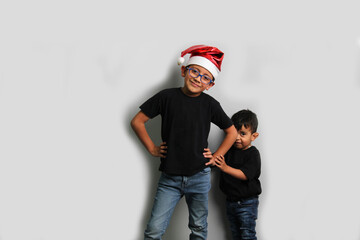 Fototapeta premium Dark-skinned Latino children, older brother in Santa hat takes care of his younger brother and spends quality time at the holidays to celebrate Christmas