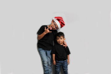 Obraz premium Dark-skinned Latino children, older brother in Santa hat takes care of his younger brother and spends quality time at the holidays to celebrate Christmas