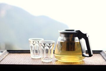 Hot tea in teapot and 2 glasses with soft focused of mountain in the background