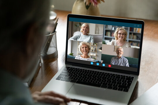 Communication on retirement. Aged male using laptop to talk with old friends retired persons online in video conference app discuss news chat about common interests. Over shoulder view on pc screen