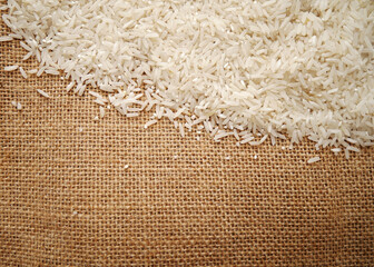 Rice grains on an old burlap sack background.