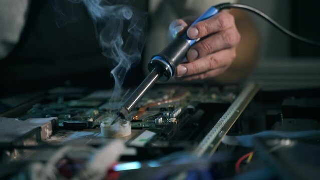 close-up of the soldering tool of a male repairman repairs laptop and soldering electronics in a  appliance repair shop