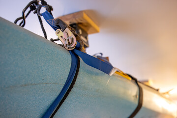 Selective focus on the side of a kayak that has used a Hoist and pulley system to store on the ceiling of a garage.