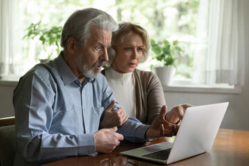 Unexpected problem with laptop. Shocked elderly spouses on pension look on pc screen getting...