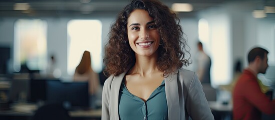 Casual woman in office smiling with phone, looking at camera.