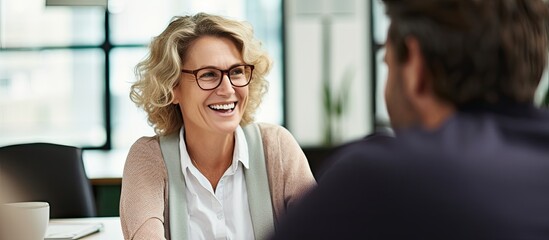 Mature woman discussing project with young man in office.