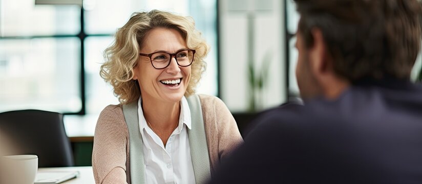 Mature woman discussing project with young man in office.