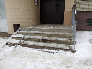 Concrete stairs at the entrance to the house with a ramp for people with disabilities.