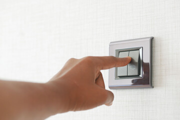 A finger turning on lighting switch .