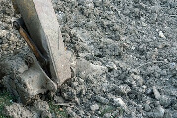 Old buckets of an excavator machine stay down on grounds in the the construction site.
