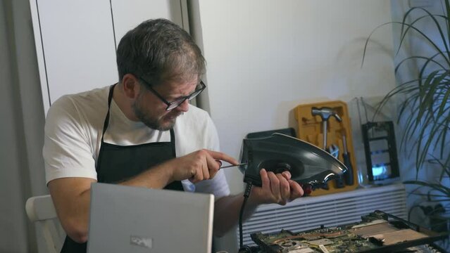 A Man Repairman Makes Repairs And Repairs An Electric Iron Iflatiron N A Home Appliance Repair Shop