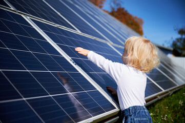 Curious boy interested in how solar panel works. Little child looking at dark blue solar battery....