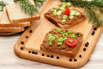 Pate spread from deer meat on whole grain bread  and green onion.  Sandwich with meat pate on cutting board, fresh tomatoes and spices for venison around. Decorated with spruce branch.