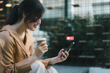 Happy young Asian woman using smartphone to interact with social media icons. Social media...