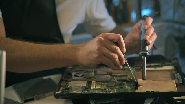 Close-up of a hand repairman specialist man doing repairs, and repairing electronics in a hardware repair shop