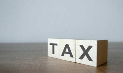 Tax - text on wooden cubes, on wooden background.