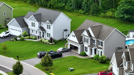 Upscale suburban homes with large backyards and green grassy lawns in summer season. Private residential houses in rural suburban sprawl area in Rochester, New York