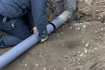 住宅の排水を下水道につなげる配管工事する人物