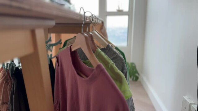 Close up video footage 4k of woman hanging colorful t-shirt in the apartment.