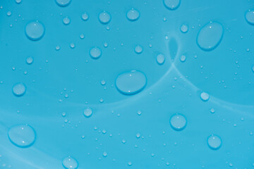 water drops on blue background. Bluewater bubbles on the surface ripples. Defocus blurred transparent white-black colored clear calm water surface texture with splash and bubbles. Water waves shining.
