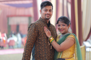 Portrait of a couple in the city. They are wearing traditional Indian dress and posing for...