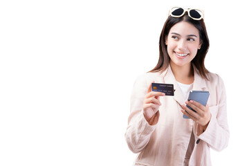 Young asian lady using mobile phone holding credit card look at copy space isolated over white background and copy space Smiling young girl purchasing online through phone by using credit card