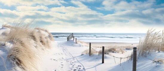 A wintry sandy beach view with snow and a distant boardwalk.