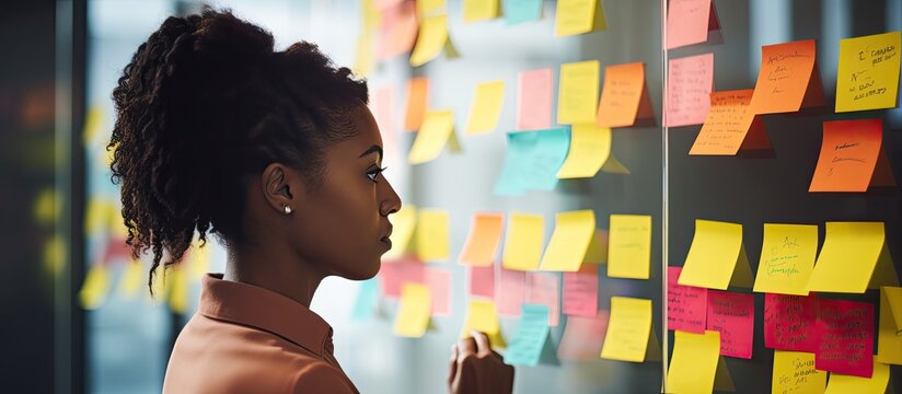 Black woman and man strategizing business expansion with brand vision, utilizing sticky notes and marketing schedule. - Powered by Adobe